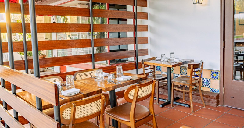 Exterior, patio with set wooden tables, cane backed chairs, and colorful tiled wall accents