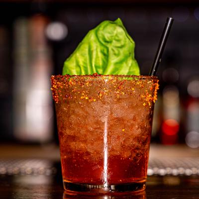 Spicy Basil Margarita served in a chili-rimmed glas, garnished with a basil leaf.
