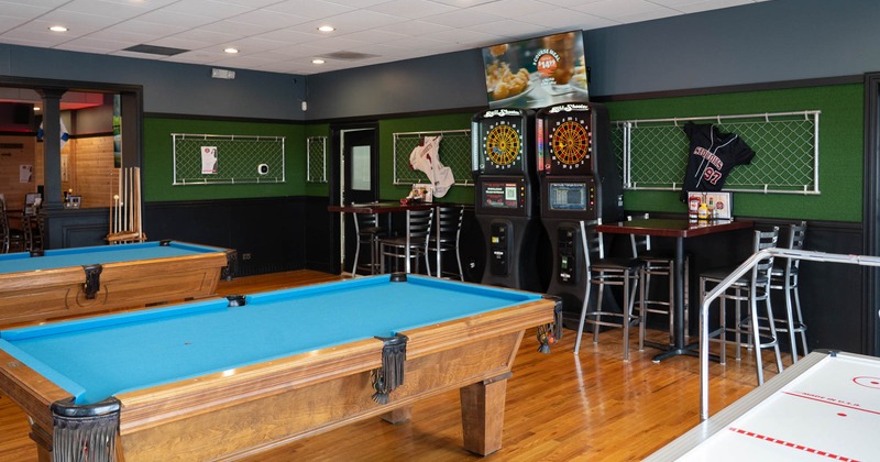 Interior, two pool tables with a dartboards in the back