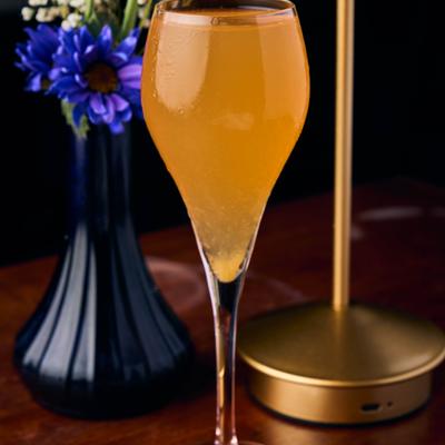 Orange cocktail served in a tall glass.