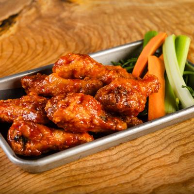 Lightly breaded wings, served with carrot and celery sticks, side view, closeup.