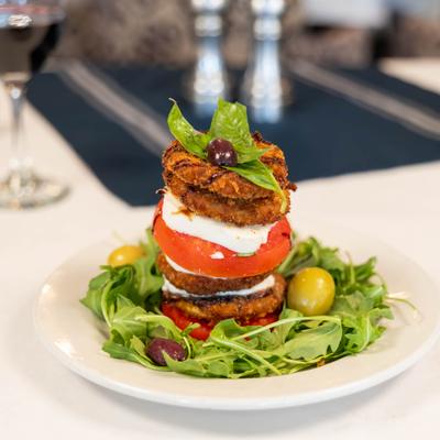 Breaded eggplant layered with feta, gorgonzola, and mozzarella, on a bed of arugula.