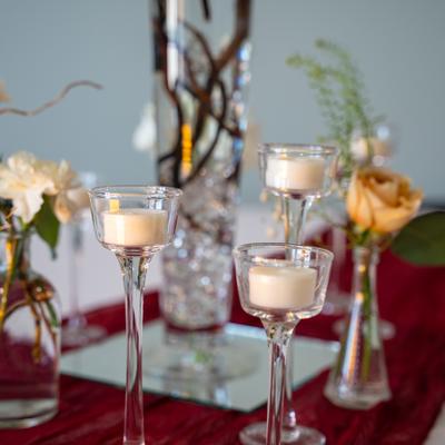 Elegant stemmed candle holders on a table with floral decorations.