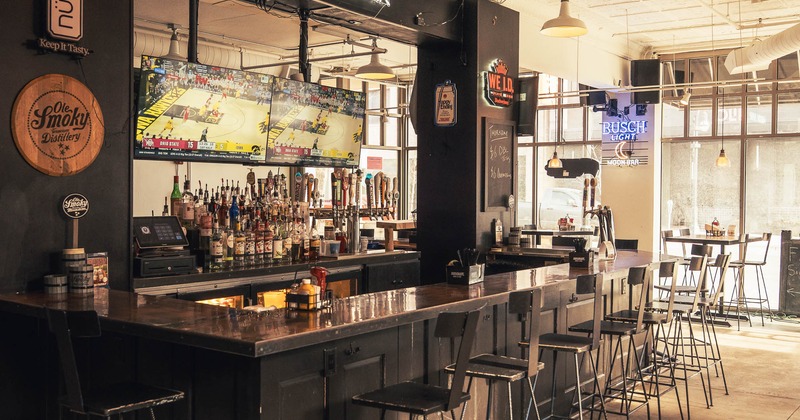 Bar area with a counter, stools, well-stocked bar shelves and TV screen