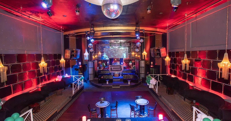 Interior with booth seating , hanging chandeliers, a central dance floor and a DJ booth