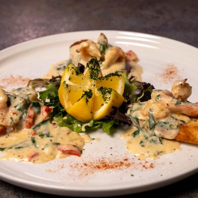 Shrimp bruschetta topped with a creamy sauce and garnished with carved lemon.