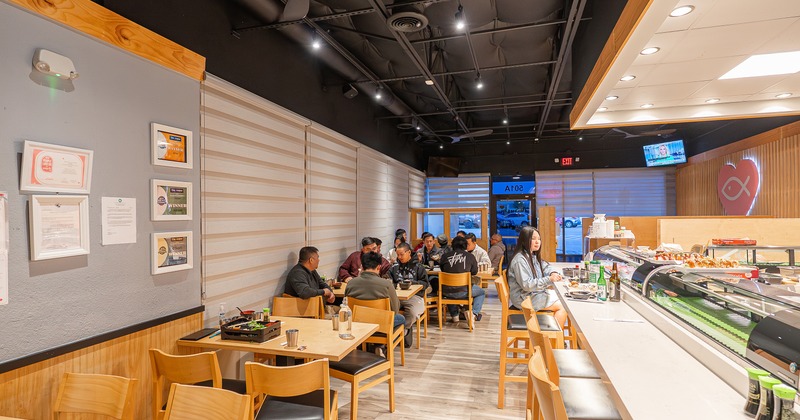 Modern sushi restaurant interior, seating area and sushi bar counter, guests enjoying their food