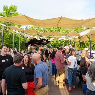 Group gathering on rooftop patio with shade sails and hanging lights.