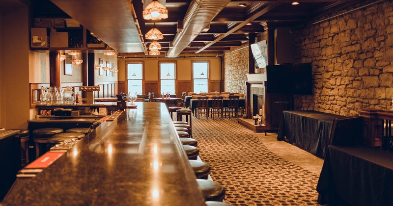 Bar with bar stools, tables and chairs in the back