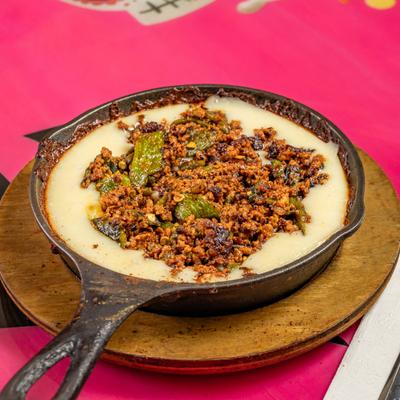 Cheese dip topped with chili, served in a skilet.