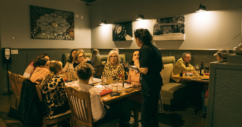 Interior, a staff member taking orders from guests