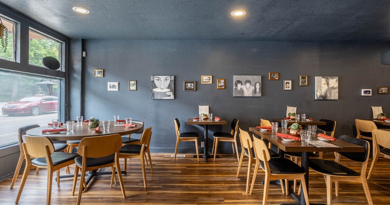 Cozy restaurant interior with wooden floors and dark walls adorned with framed artwork