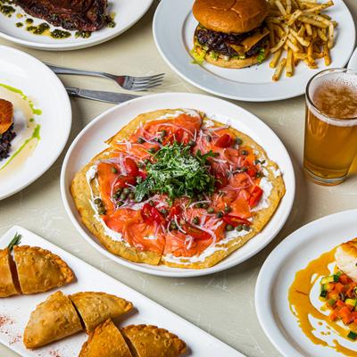 Assortment of food dishes, wine and a glass of beer on a table.