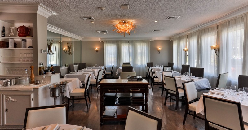 Elegant restaurant interior with set tables, and large windows with curtains