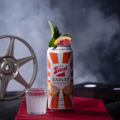 Stiegl Grapefruit Radler can garnished with mint and grapefruit slice, next to a drink shot.