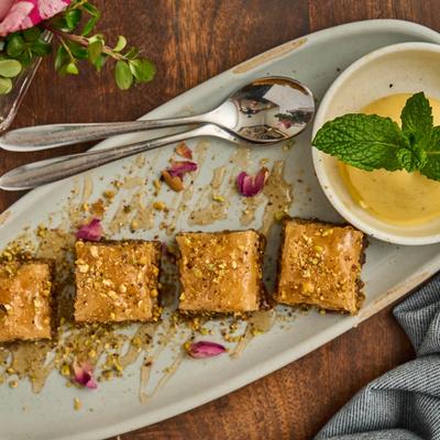 Baklavas with ice cream on the side, on a plate garnished with petals.