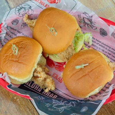 Fried chicken sliders in a basket lined with printed paper.