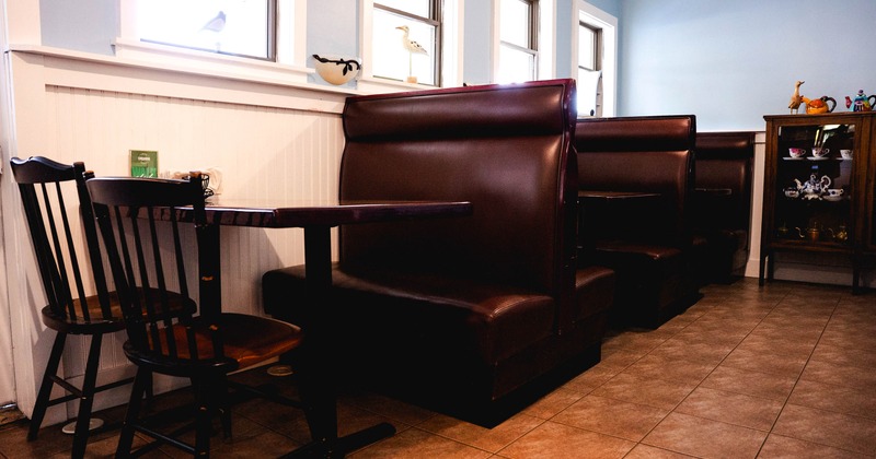 Interior, wooden chairs and brown leather booths, light blue walls, decorative items