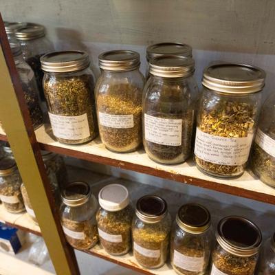 multiple jars of different loose leaf teas sitting on shelves of a book case.