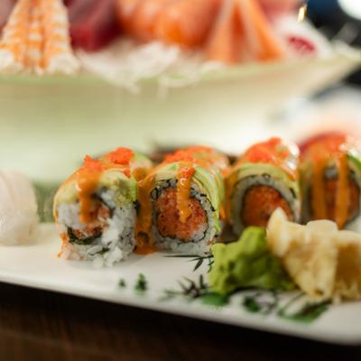 Sushi love boat platter with assorted rolls and sashimi, close-up.