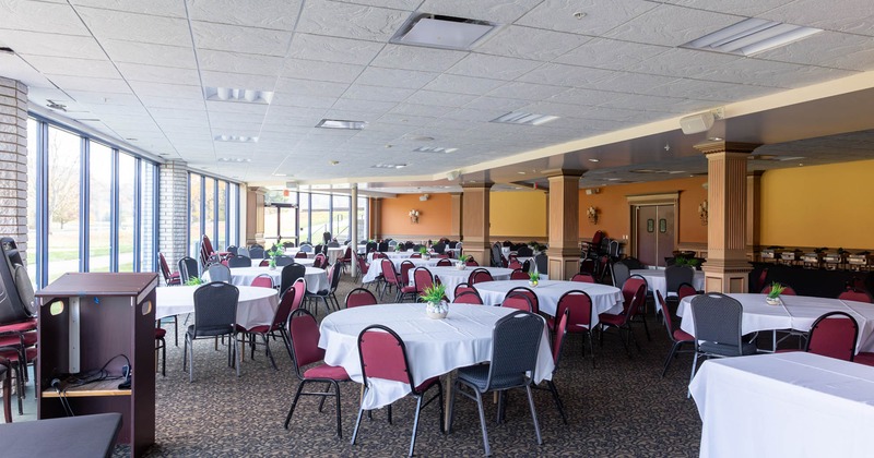 Interior, banquet hall, round dining tables for eight, carpet flooring, large windows