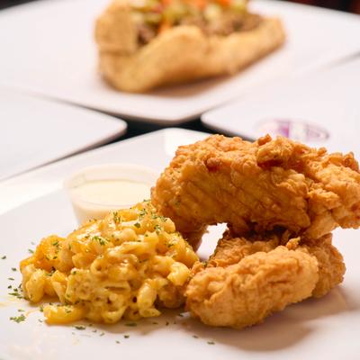 Chicken tender with mac and cheese alongside other dishes on the table.