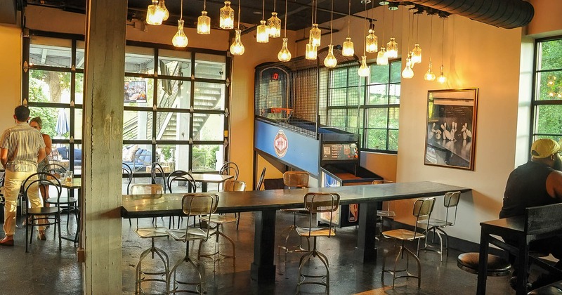 Interior, long tables with bar chairs and a basketball arcade machine in the back