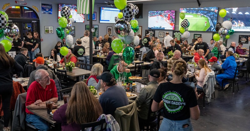 Interior, dining area with tables, chairs, balloon decorations and TV screens on the wall