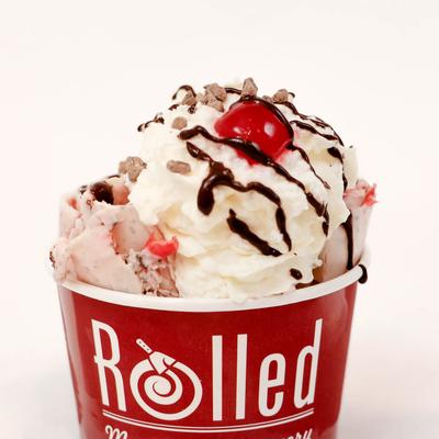 Pink ice cream with whipped topping and cherry.