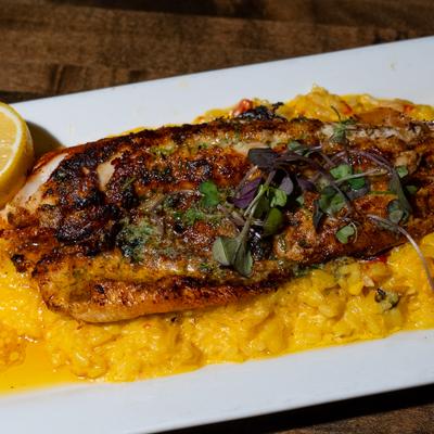Louisiana Walleye served with saffron red pepper risotto, and a lemon wedge.