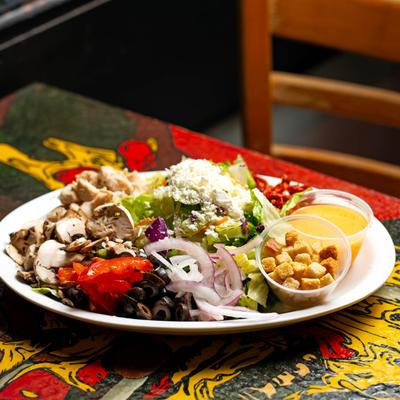 Dinner salad with mushrooms, peppers, lettuce, olives, onions, and croutons.
