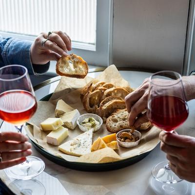 Two people sharing a cheese plate and wine.