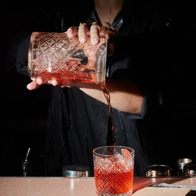 Bartender pouring a Negroni cocktail.