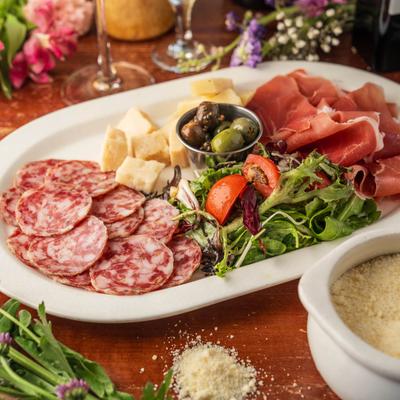 Charcuterie board featuring cured meats, green salad and olives.