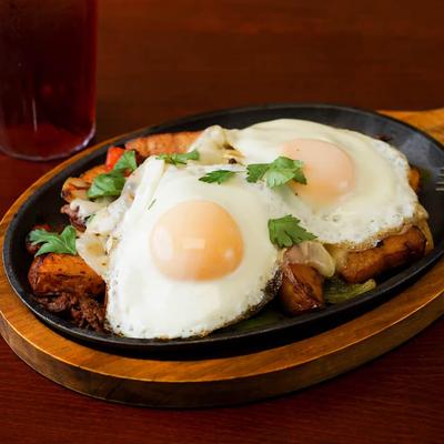 Pot roast hash skillet with seasoned potatoes, peppers, melted cheese, and two fries eggs.