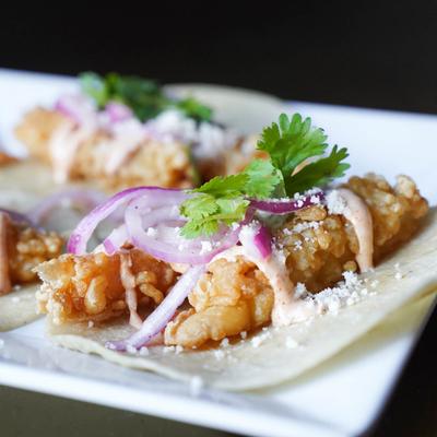 Crispy shrimp tempura tacos topped with pickled red onions, ancho crema, and cotija cheese.