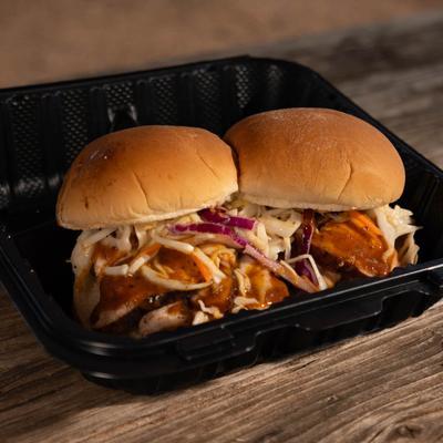 Two brisket sandwiches on a bun topped with spicy coleslaw.