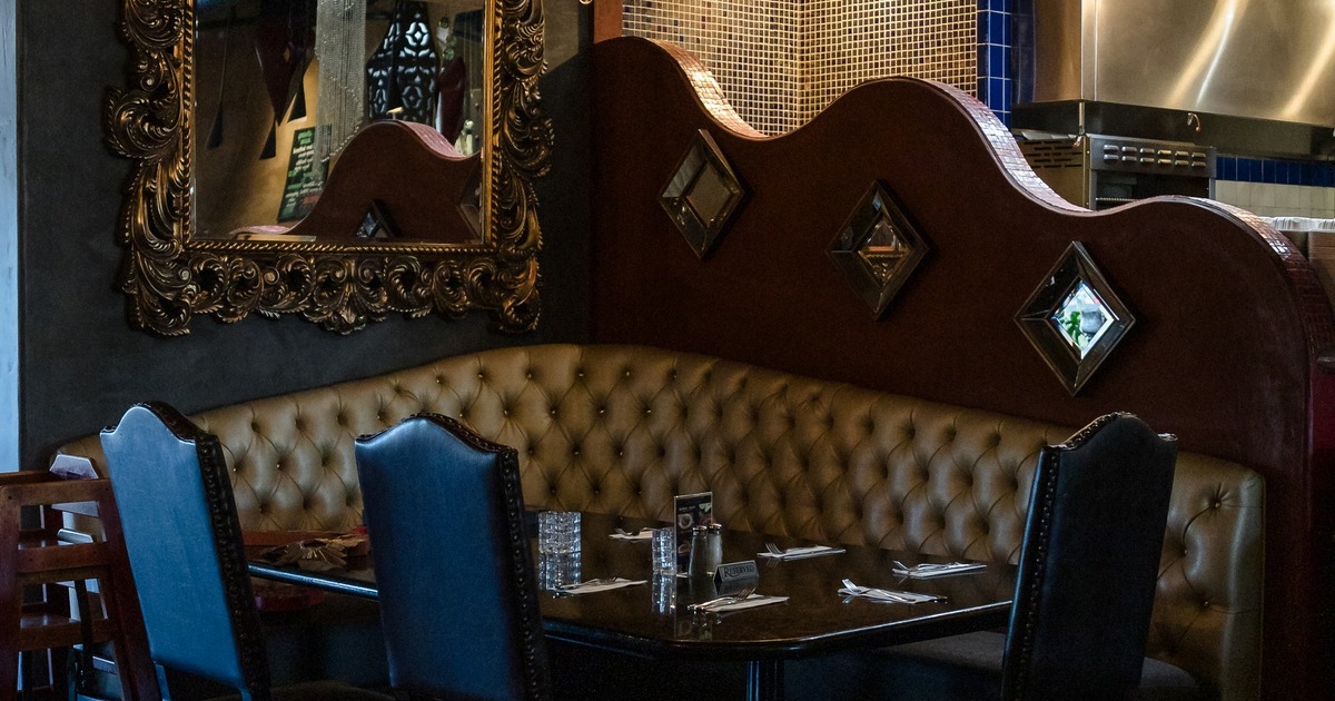 Interior, dining area with massive leather couch and table with chairs, massive golden frame mirror
