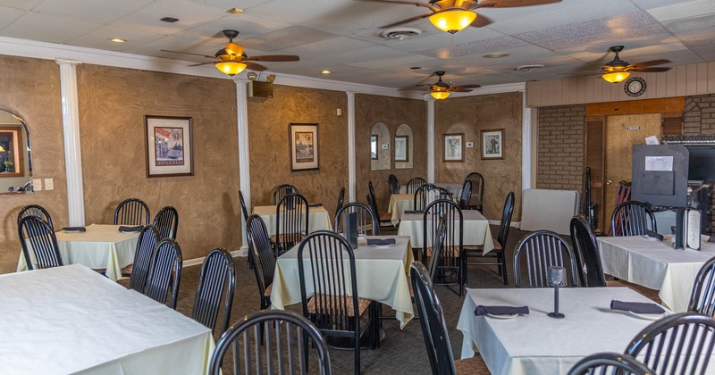 Interior, white cloth tables for four, ceiling fans, framed pictures, carpet flooring