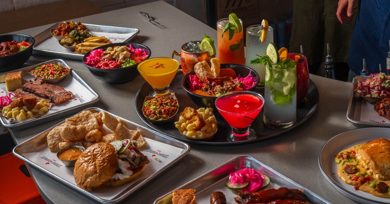 Assortment of dishes and cocktail drinks spread on a bar counter