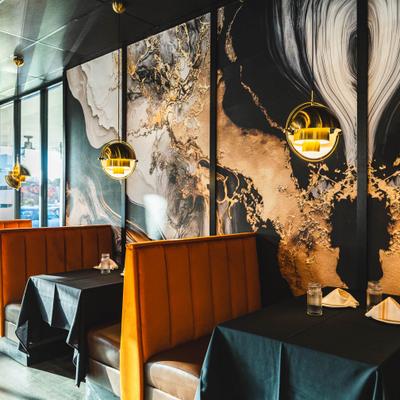 Stylish interior, orange booths, black tablecloths, gold pendant lights and gold and black wall art.