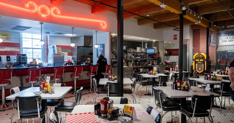 Interior of a vintage-style diner with red stools, neon lights, and a jukebox