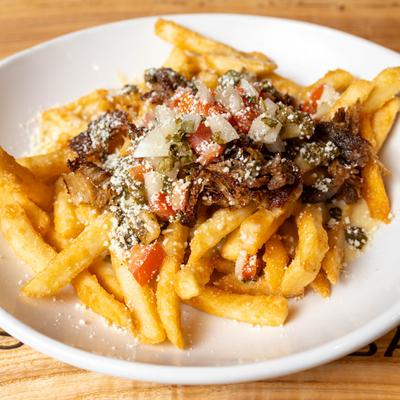 Loaded fries, with shredded beef, cheese sauce, pico de gallo, chimichurri, and cotija.