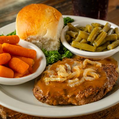 Angus Chopped Steak with gravy, served with green beans, carrots, and a bread roll.
