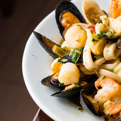 Seafood pasta with mussels in a white bowl.