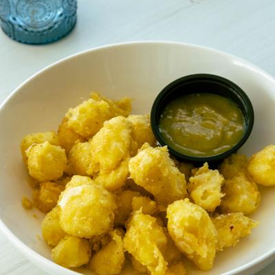Fried cheese curds served with a green dipping sauce.