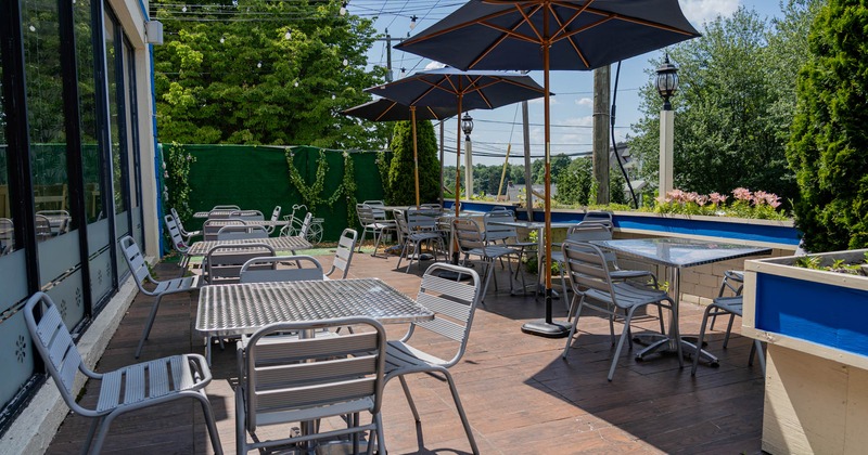 Exterior, partially covered seating area, tables and chairs under parasols, wooden deck