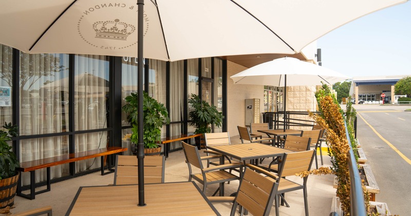 Exterior, partially covered seating area, tables and chairs under parasols