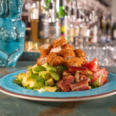 Southern Cobb salad, with fried chicken, onion, tomato, avocado, cheese, nuts, and corn.