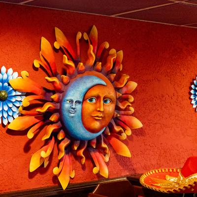 Wall art featuring a 3D resin sun and moon face set against metal rays.